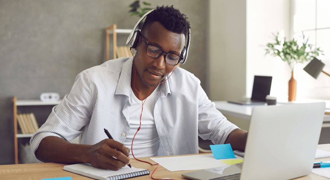 black male , writing on the note , headphones 