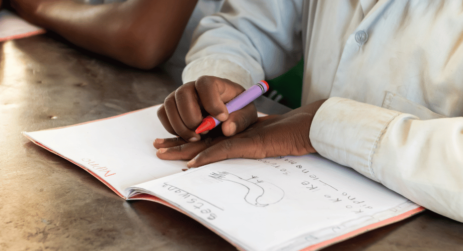 learner holding the crayon on his hand , exercise book 